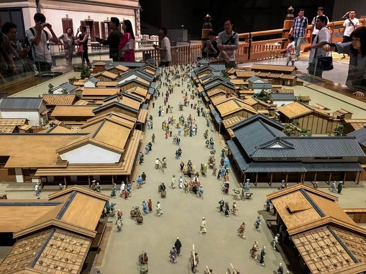 a group of people standing around a model of a city