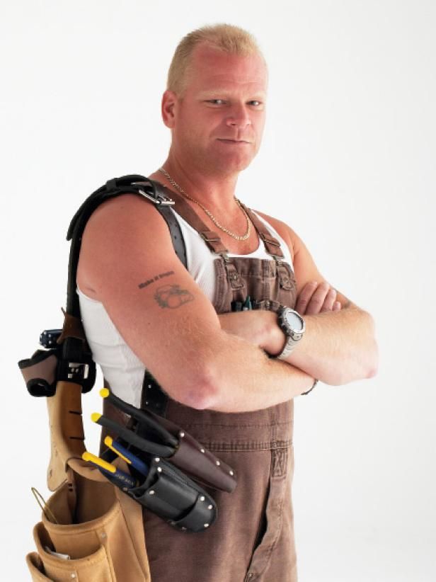 a man with his arms crossed standing in front of a white background wearing construction equipment