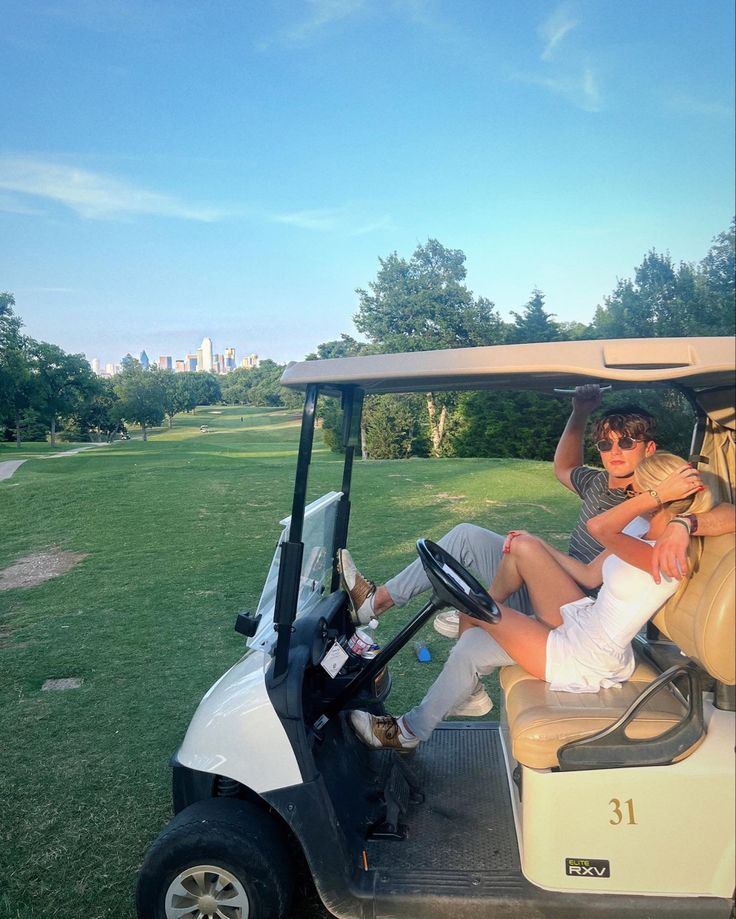 two people sitting in a golf cart on the grass