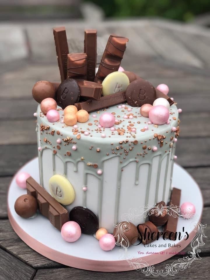 a white cake with chocolate and candy toppings on it sitting on a wooden table