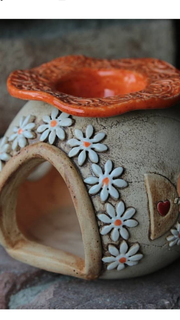 a ceramic vase with flowers on it sitting on a stone surface next to a rock