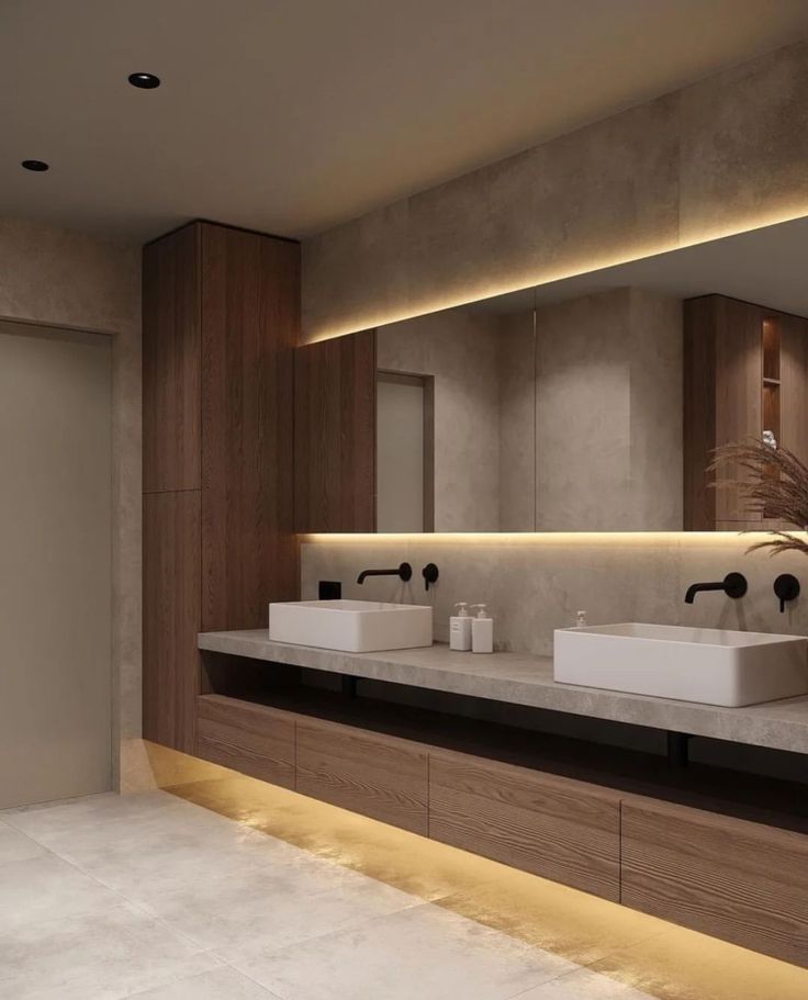 a modern bathroom with two sinks and large mirrors on the wall above them is illuminated by recessed lighting