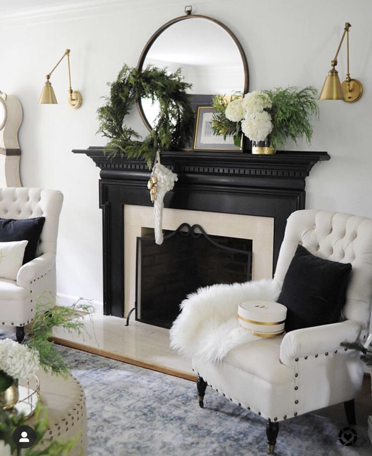 a living room decorated for christmas with white furniture and greenery on the mantel