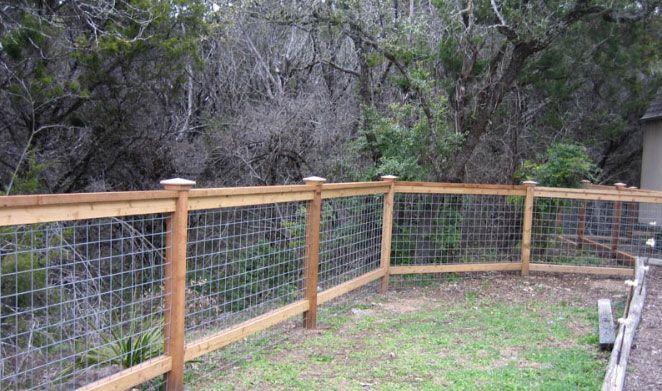 a wooden fence with wire around it in the middle of a yard next to trees