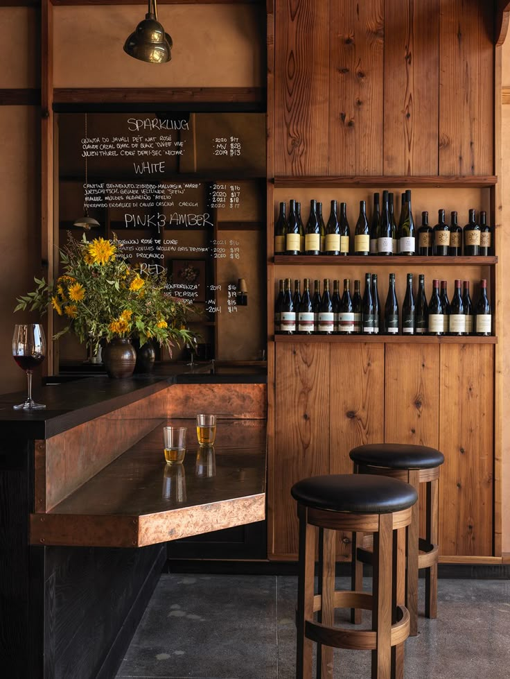 there is a bar with bottles on the wall and two stools in front of it