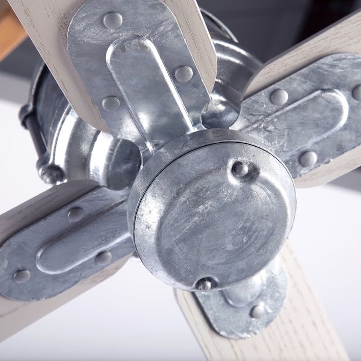 a close up view of a ceiling fan made out of metal pipes and wooden beams