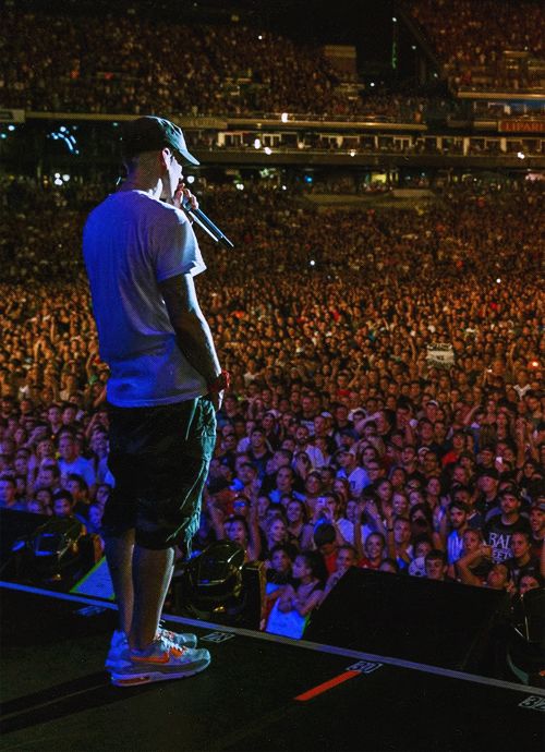 a man standing on top of a stage in front of a crowd at a concert