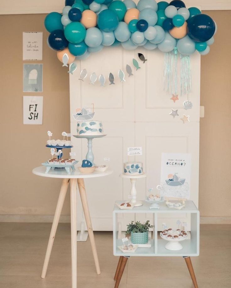 a table topped with balloons and desserts next to a white door in a room