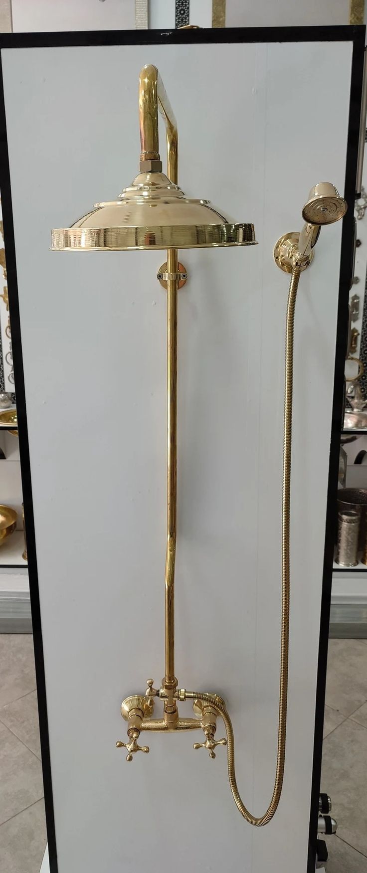 an old fashioned shower head and handset in a store display case with gold fixtures