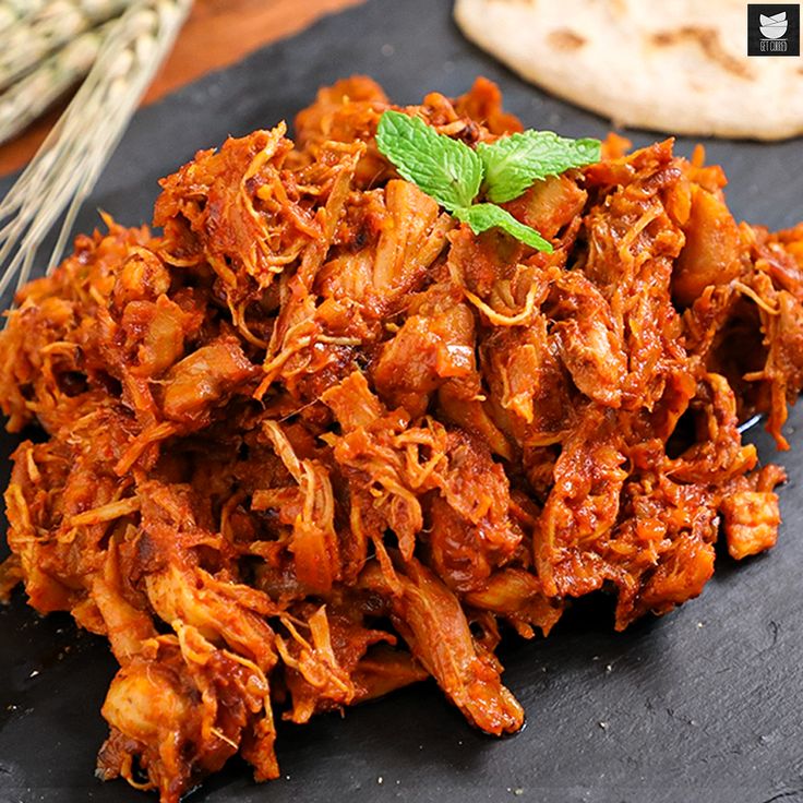 a pile of shredded meat sitting on top of a black plate next to some bread