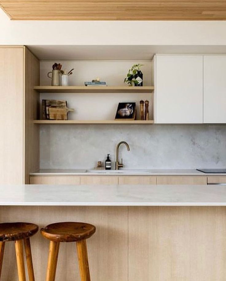 two stools sit in front of an island counter top with built - in shelving