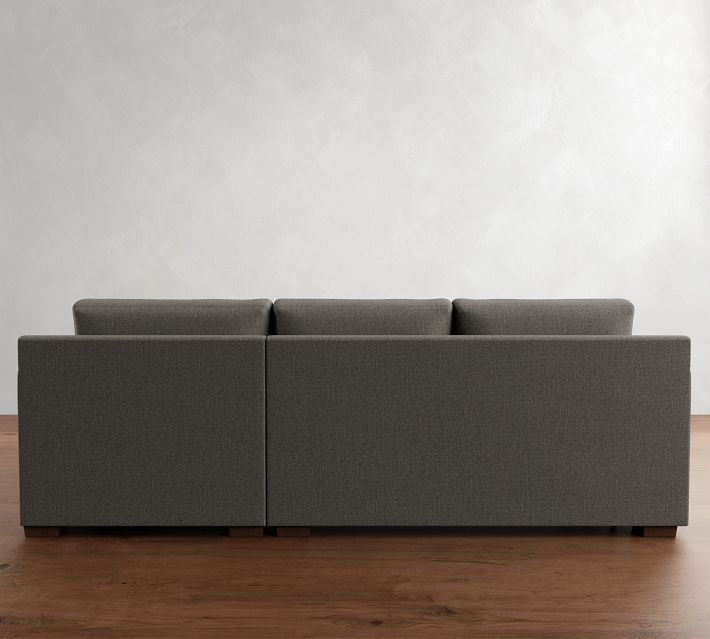 a gray couch sitting on top of a wooden floor next to a white wall in an empty room