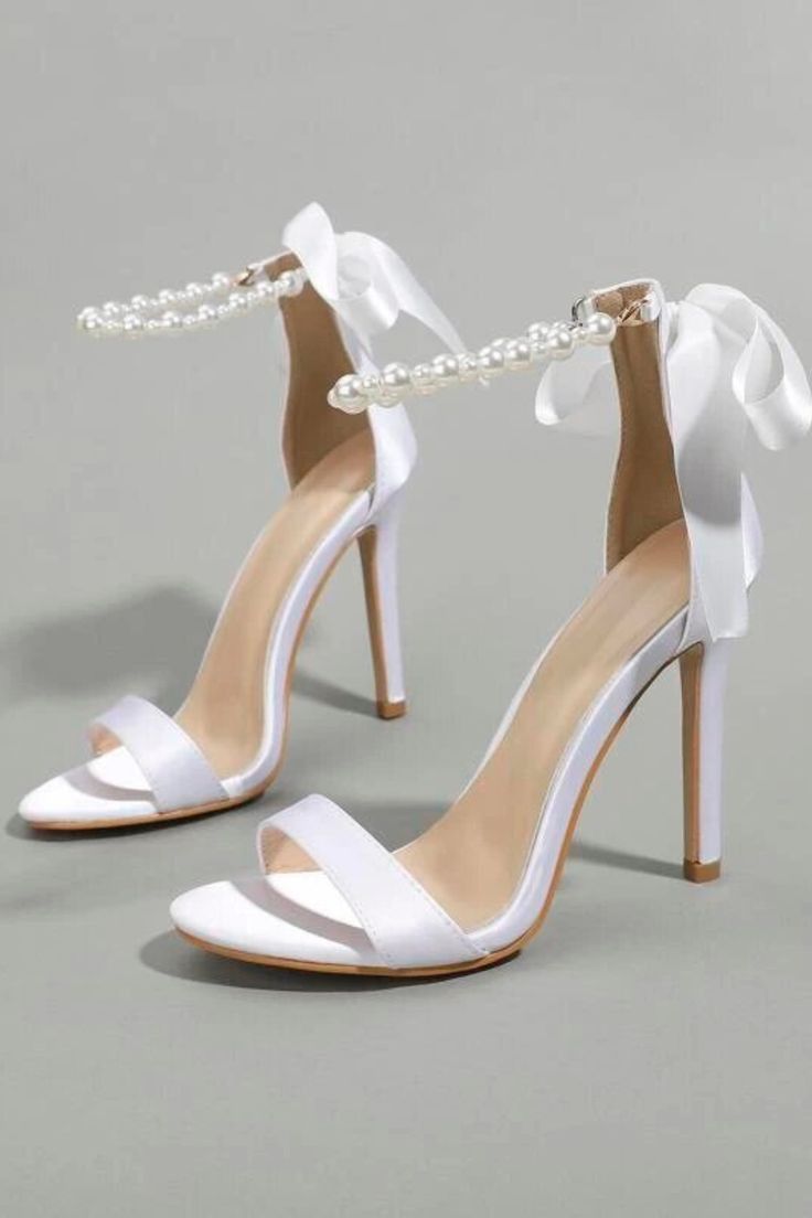 a pair of white high heeled shoes with pearls on the ankle and heels are shown