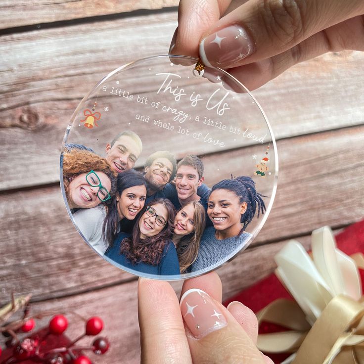 a person holding up a glass ornament with photos on it