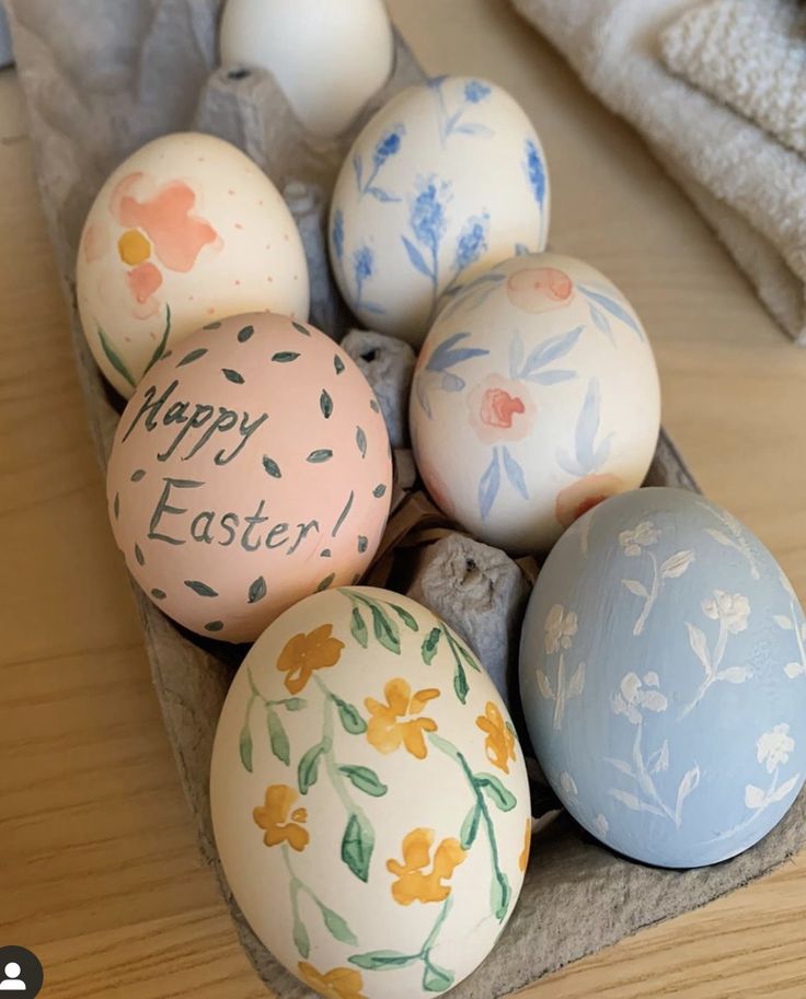 an arrangement of painted easter eggs on a tray with the words happy easter written on them