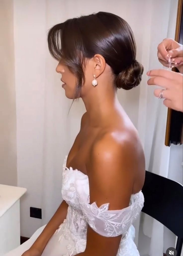 a woman in a wedding dress getting her hair done