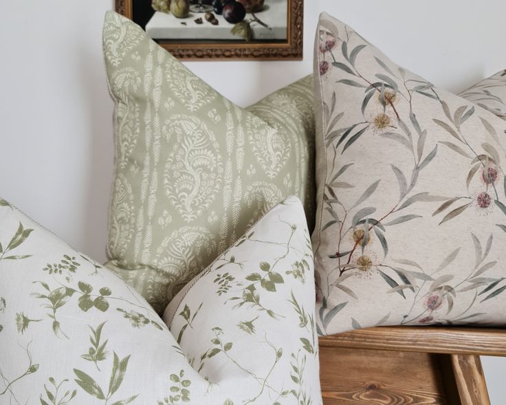 two pillows sitting next to each other on top of a wooden chair in front of a painting