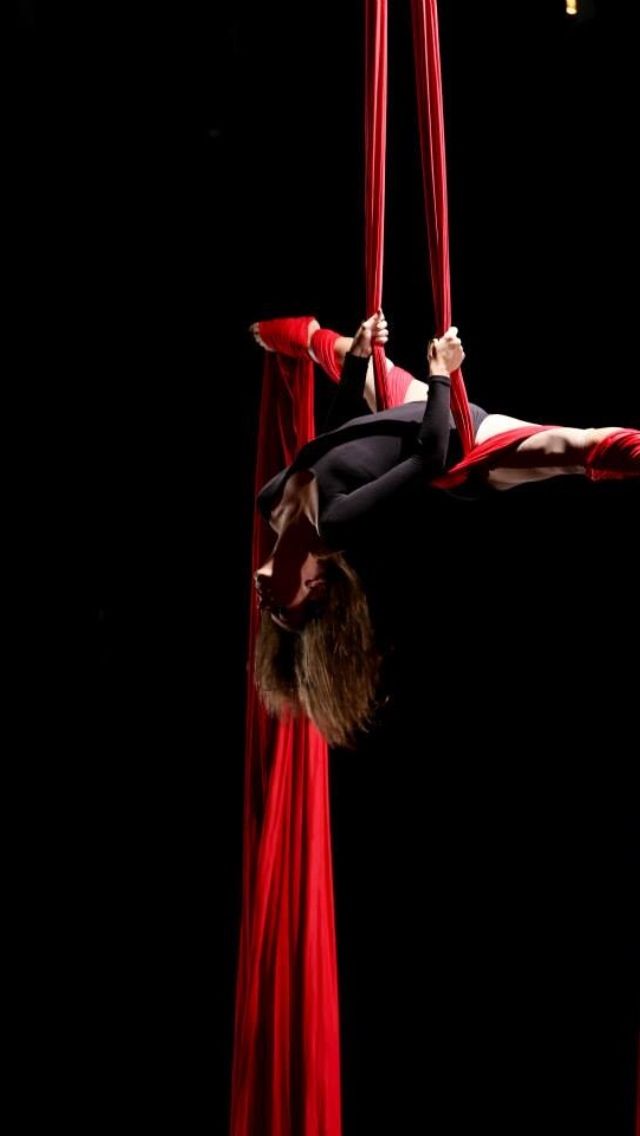 a woman is performing aerial acrobatic tricks in the dark