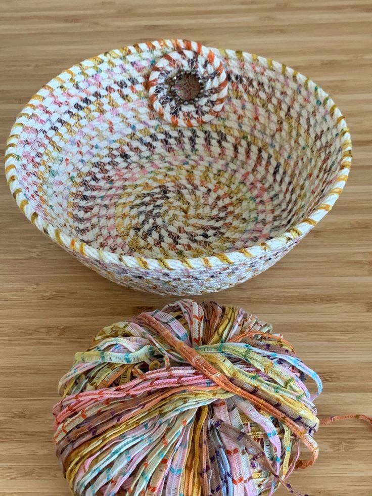 a ball of yarn sitting on top of a wooden floor next to a basket filled with yarn