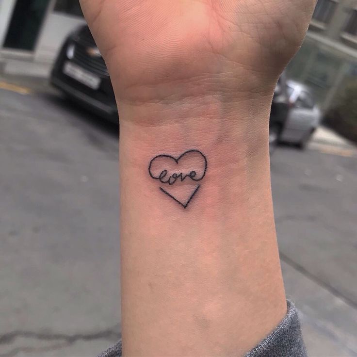 a small wrist tattoo with the word love on it