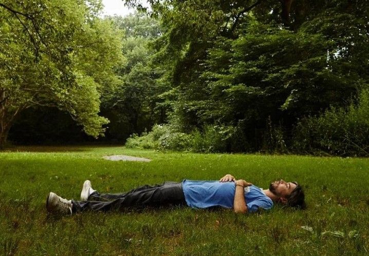 a man laying in the grass with his eyes closed