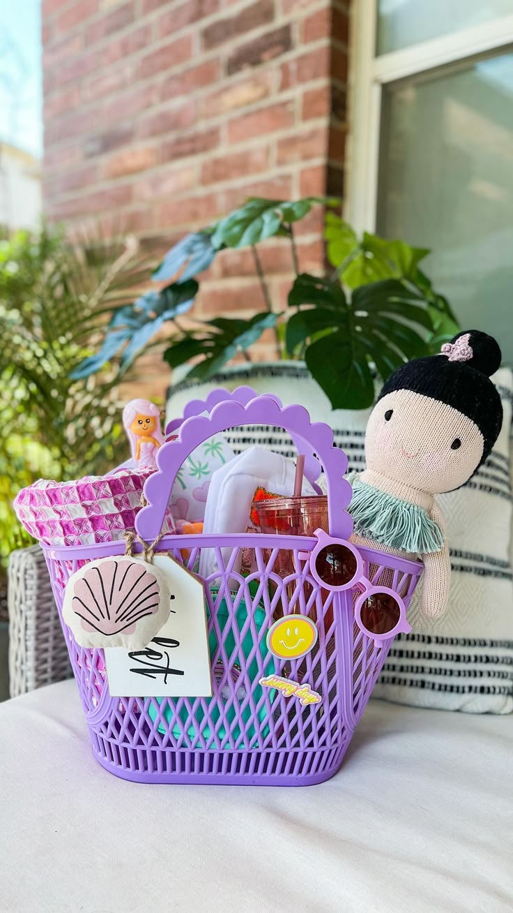 a purple basket filled with toys sitting on top of a table next to a potted plant