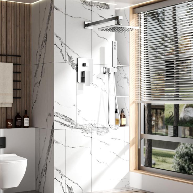 a white toilet sitting next to a window in a bathroom under a shower faucet