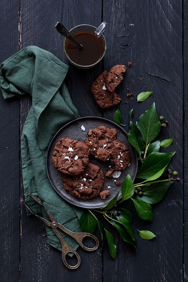 chocolate cookies with sea salt on a plate next to a cup of tea and green leaves