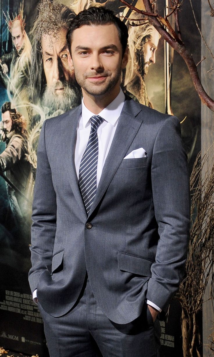 a man in a suit standing next to a movie poster