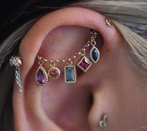 a woman wearing ear piercings with different colored stones