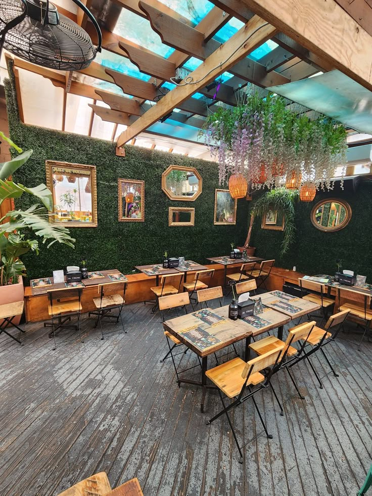 an outdoor dining area with tables, chairs and potted plants on the side wall