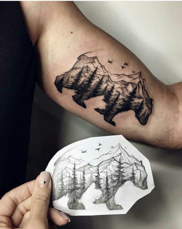 a man's arm with mountains and trees tattoo on the left side of his arm