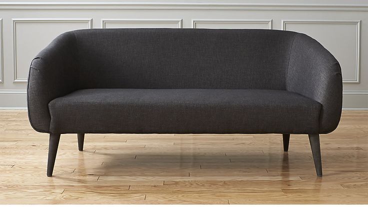 a gray couch sitting on top of a hard wood floor next to a white wall