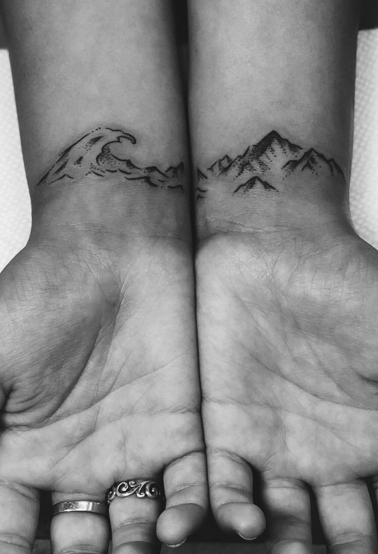 two hands with mountains tattooed on them