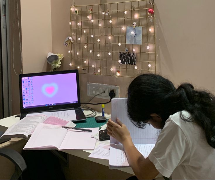 a woman sitting at a desk in front of a laptop computer with her head down