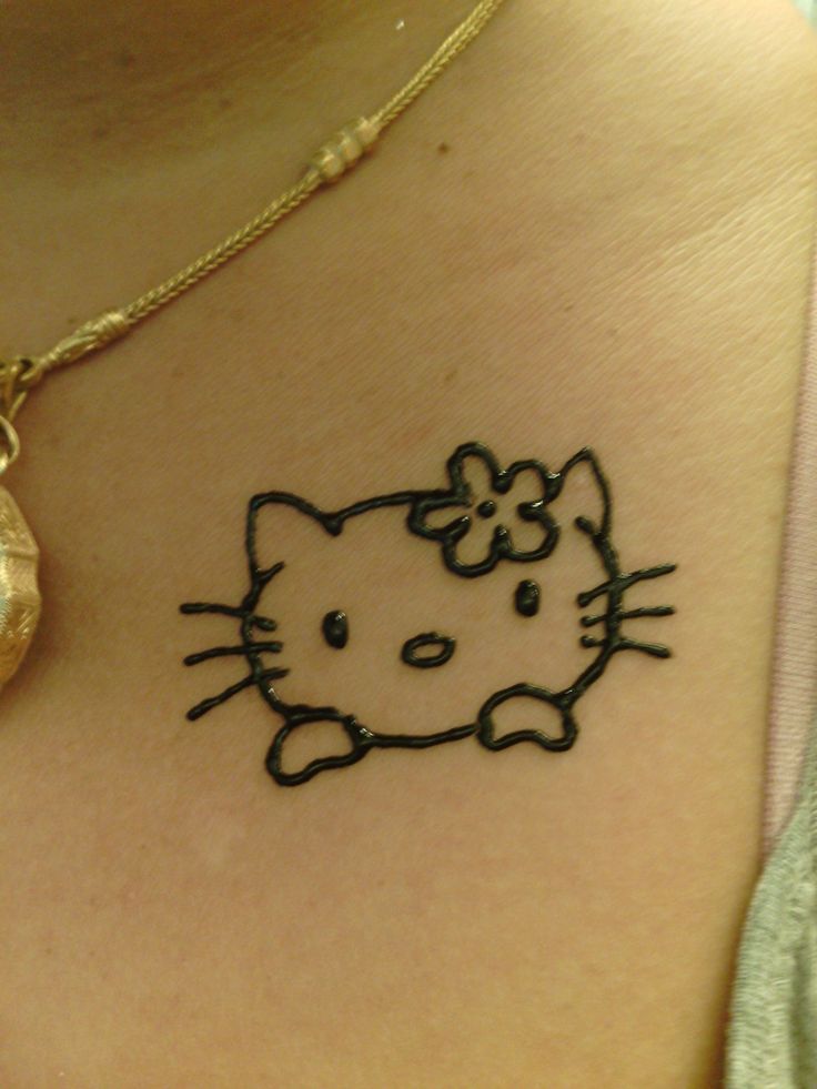 a hello kitty tattoo on the back of a woman's shoulder