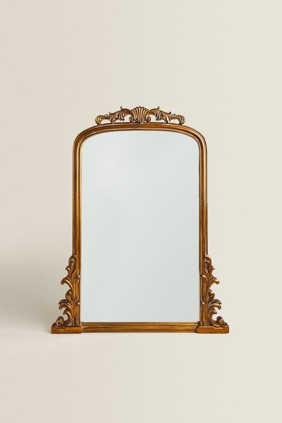 an ornate gold framed mirror against a white wall