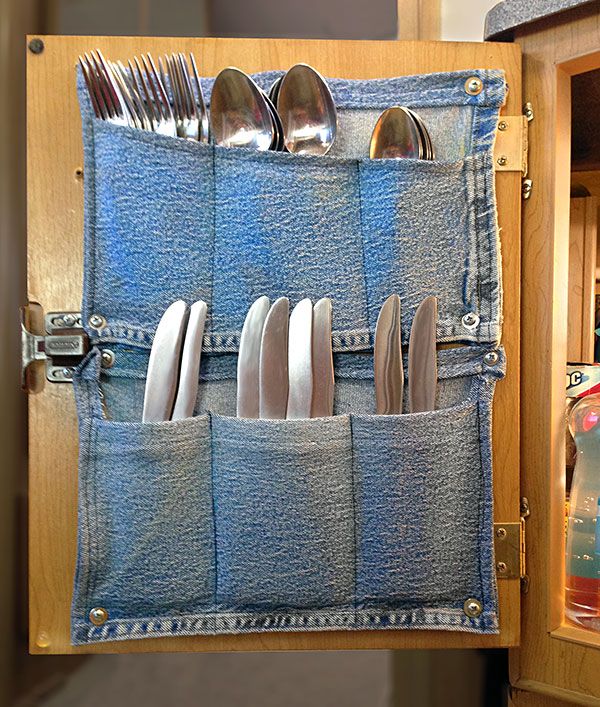 an open denim pocket holds silverware and utensils in front of a wooden cabinet