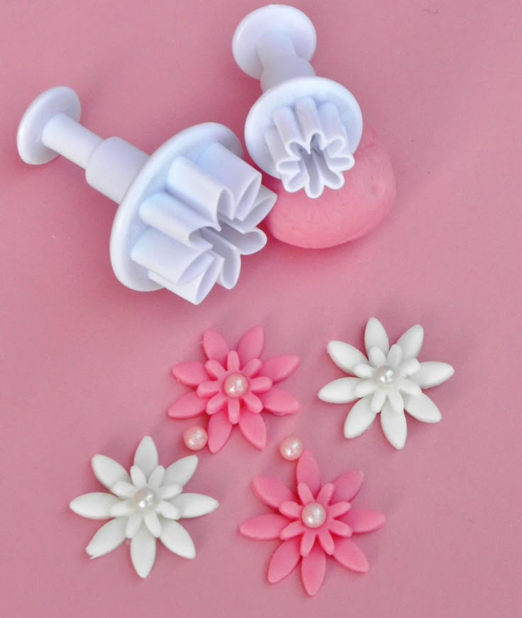 some pink and white flowers are next to a soap dispenser on a pink surface