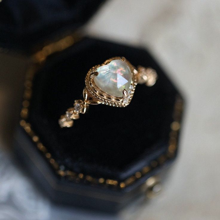 a ring with a white stone in it sitting on top of a black velvet box