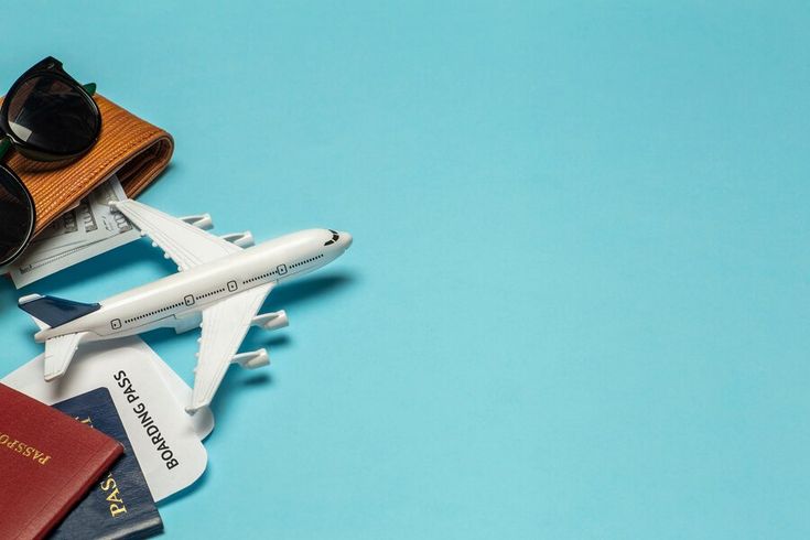 an airplane, sunglasses and passport on a blue background