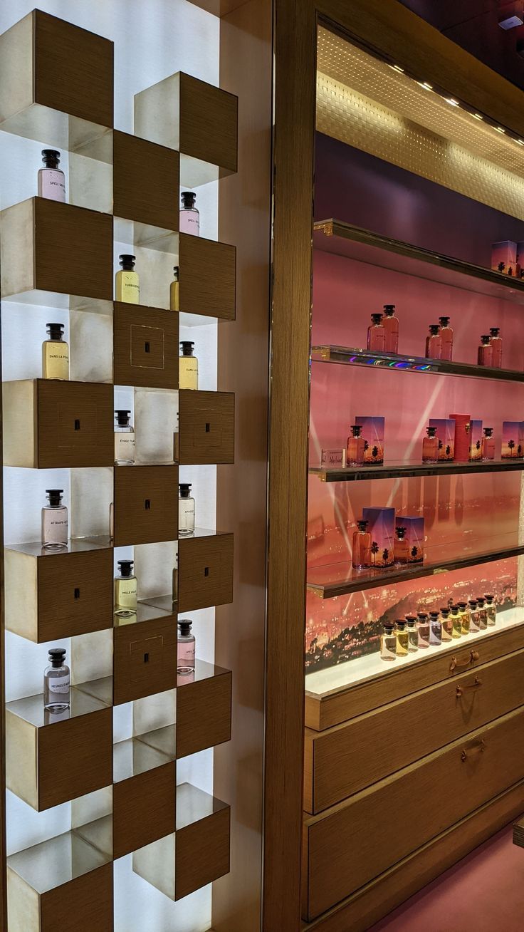 a display case filled with lots of different types of perfumes on wooden shelving