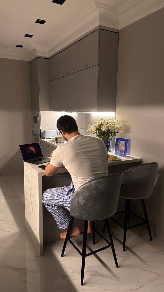 a man sitting at a kitchen counter working on his laptop