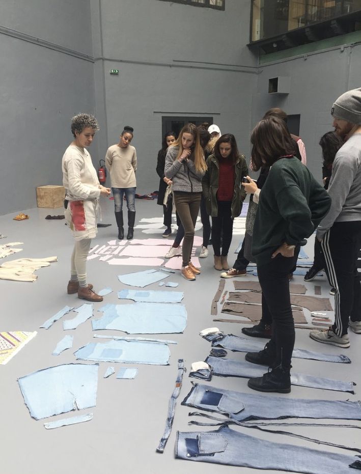 a group of people standing around in a room with pieces of paper on the floor