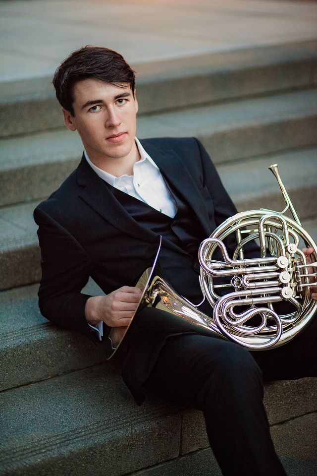 a man sitting on steps holding a french horn