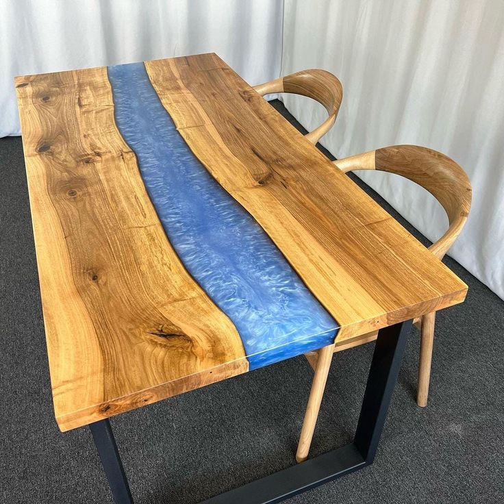 a table made out of wood and blue fabric on the top, sitting in front of a white curtain