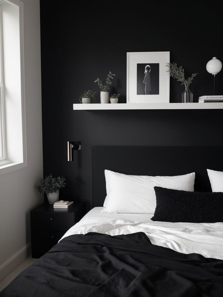 a black and white bedroom with some plants on the shelf above the bed, along with two framed pictures