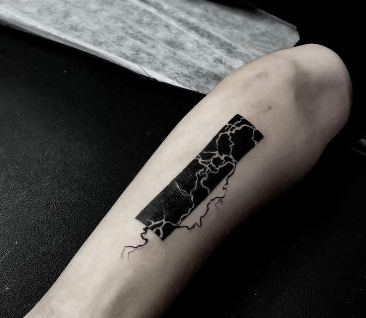 a black and white map tattoo on the left arm, with lightning coming from it