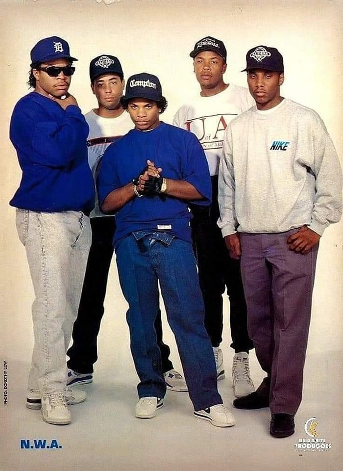 a group of young men standing next to each other wearing baseball caps and sunglasses on their heads