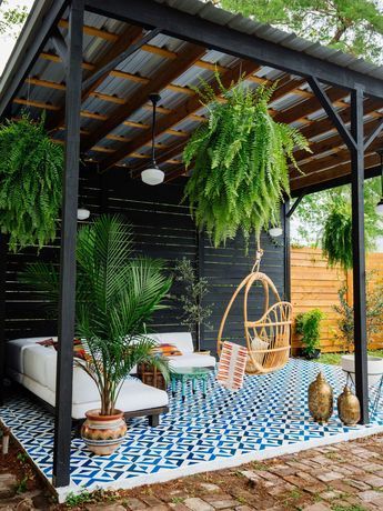 an outdoor living area with potted plants and hanging chairs on the side of it